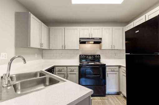 A kitchen with black appliances and white cabinets.