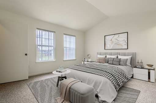 A bedroom with a large bed and a window with blinds.