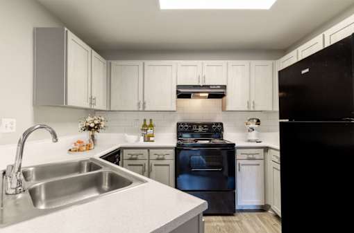 A kitchen with black appliances and white cabinets.