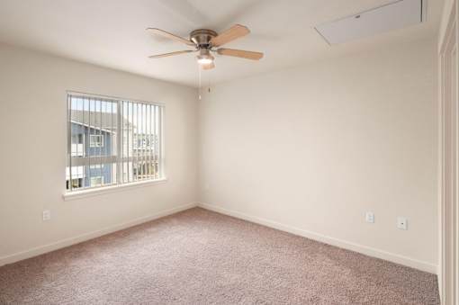 A room with a ceiling fan and a window with blinds.