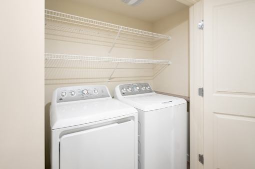 Two white front load washing machines in a laundry room.
