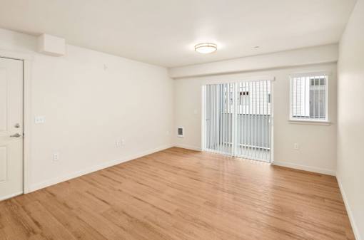 A room with wooden flooring and a window with bars.