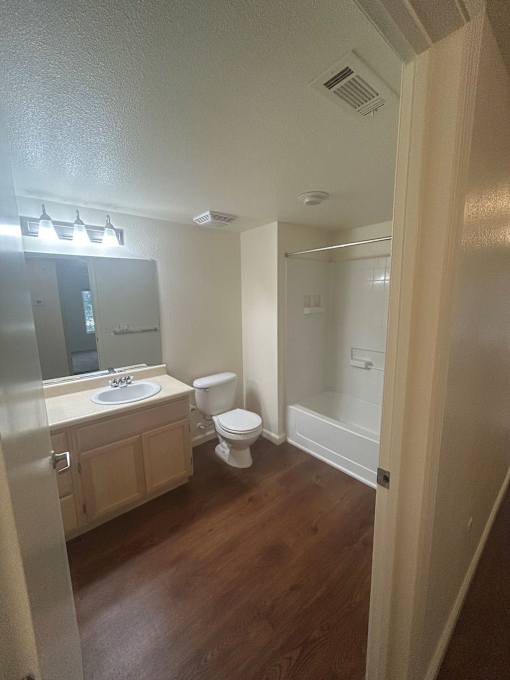 A bathroom with a toilet, sink, and mirror.