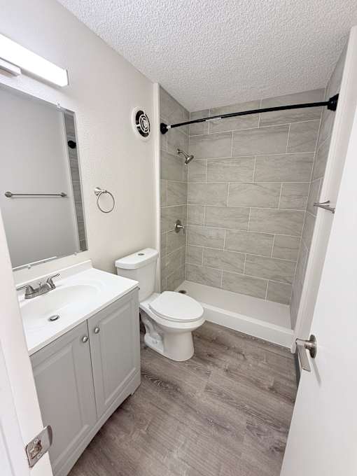 A white bathroom with a toilet, sink, and shower.