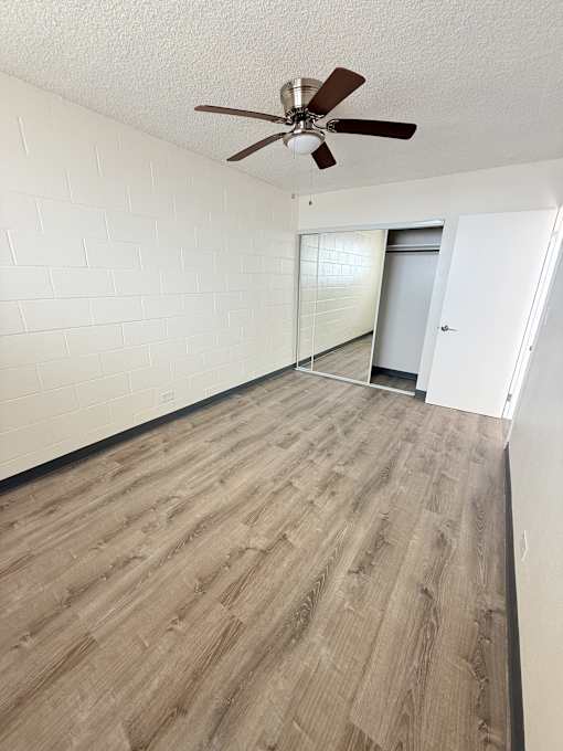A room with a ceiling fan and wooden flooring.