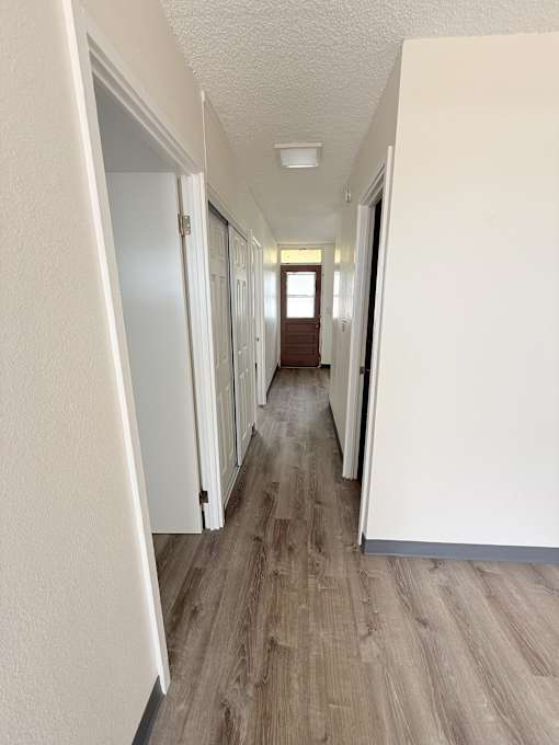 A long hallway with white walls and wood flooring.