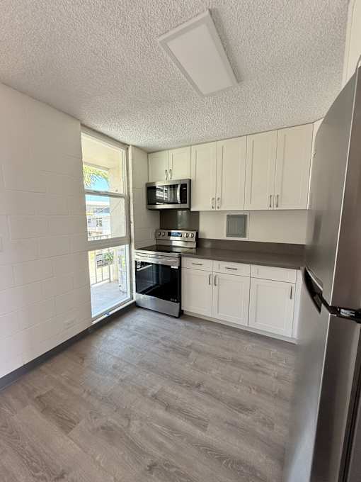 A kitchen with white cabinets and a stainless steel refrigerator.