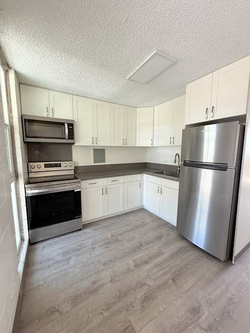 A kitchen with a refrigerator, oven, and microwave.