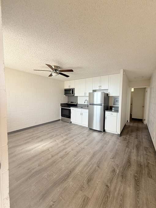A kitchen with white cabinets and a refrigerator.