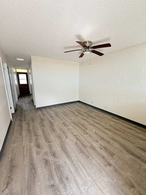 A room with a ceiling fan and wooden flooring.