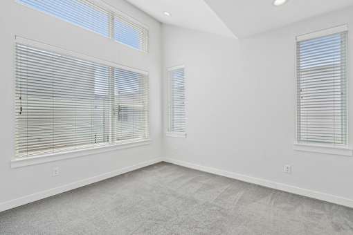 A room with two windows covered in blinds.