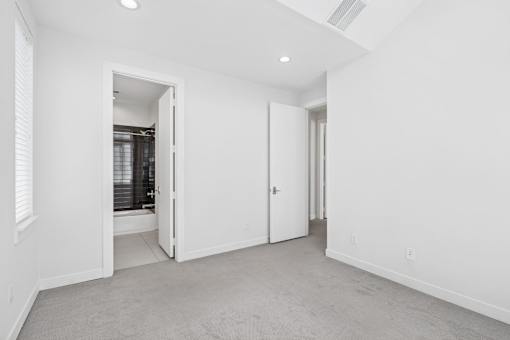 A white room with a carpeted floor and two open doors.
