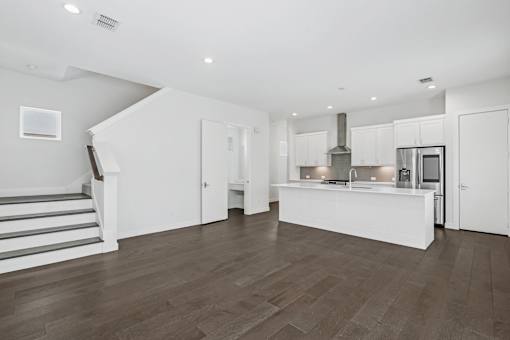 A modern kitchen with a staircase on the left side.