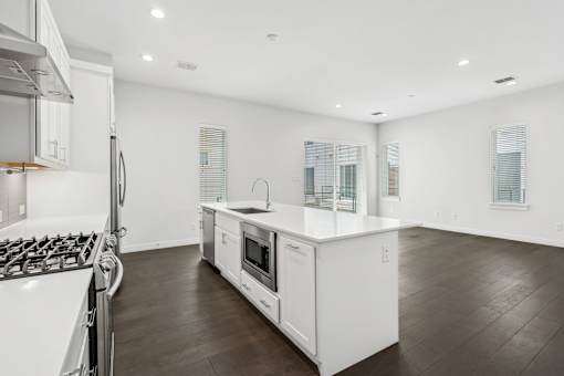 A modern kitchen with white appliances and wooden floors.