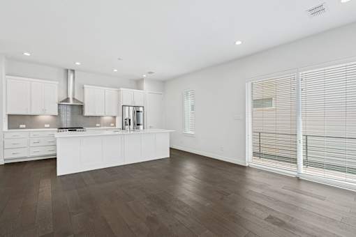 A modern kitchen with white cabinets and a wooden floor.