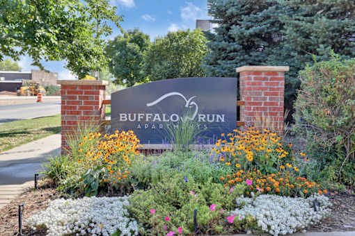A sign for Buffalo Run Apartments is surrounded by flowers.