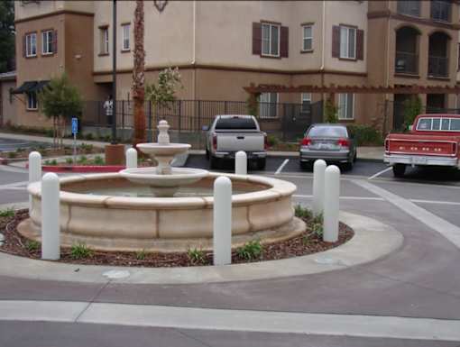 A fountain in the middle of a roundabout with a building in the background.