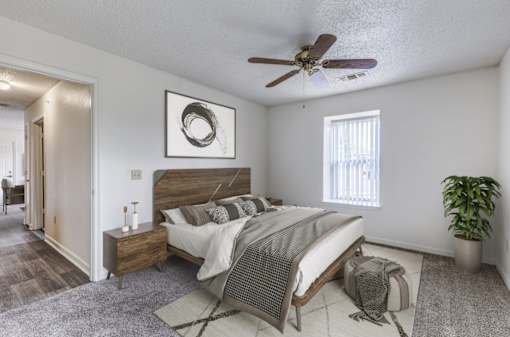 A bedroom with a bed, nightstand, and a ceiling fan.