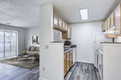 A kitchen with a refrigerator, cabinets, and a dining table.