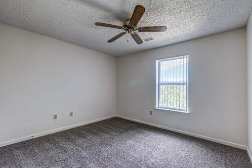 A room with a ceiling fan and a window letting in natural light.