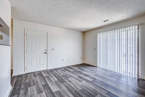 A room with a white door and a window with white blinds.