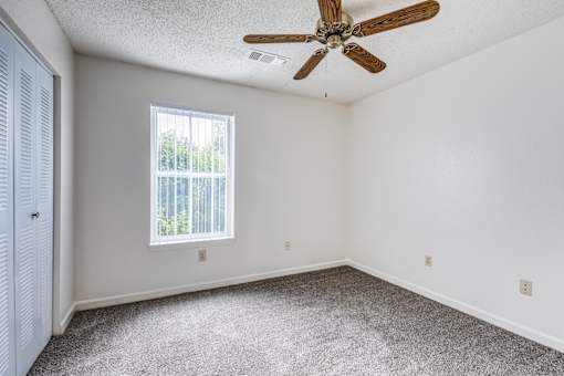 A room with a ceiling fan and a window with blinds.