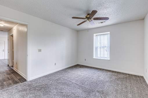 A room with a ceiling fan and a window with blinds.