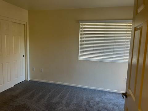 A room with a carpeted floor and a window with blinds.