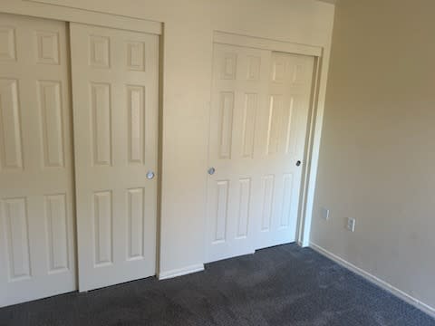 A room with two white doors and carpeted floor.
