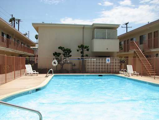 A pool in front of a building with a tree in the background.