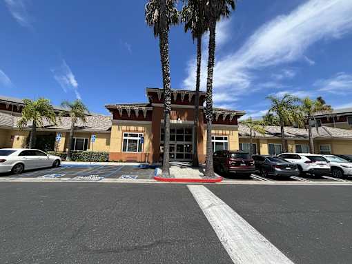 Irvine Inn parking lot with a white car parked in front of a building with a palm tree in front of it.