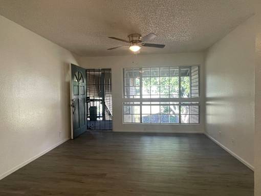 Cluster Park living room with a ceiling fan and a door leading to a balcony.