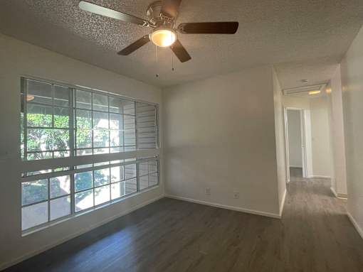 Cluster Park living area with a ceiling fan and a window with blinds.