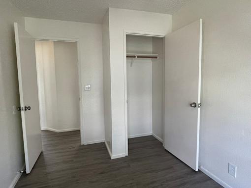 Cluster Park bedroom with a closet and dark wood like floors