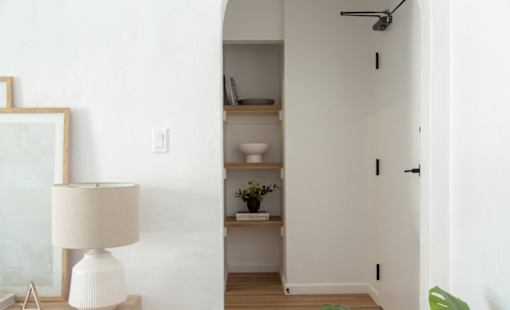 A white lamp stands next to a white wall.