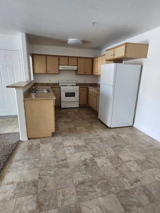 A kitchen with a white refrigerator, white oven, and white cabinets.