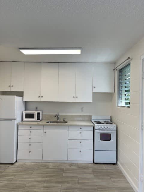 A kitchen with white appliances and cabinets.