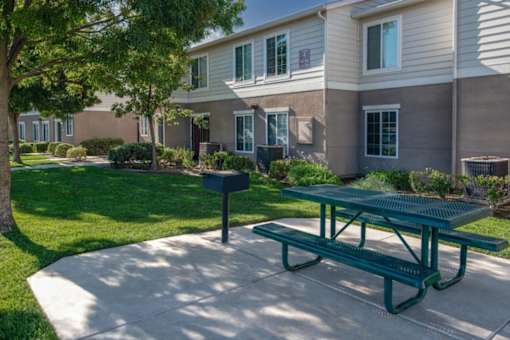 A green picnic table is in front of a building with a mailbox.