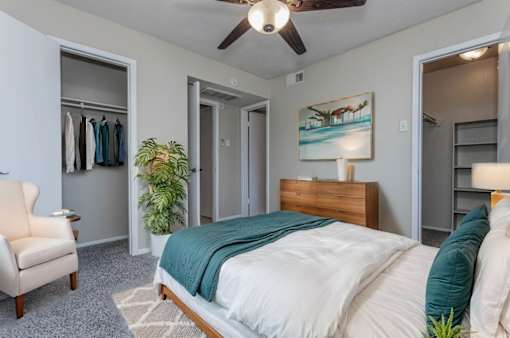 A bedroom with a bed, chair, and painting on the wall.