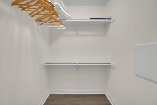 A white closet with a shelf and a hanger rack.