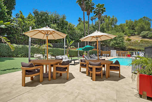 A patio with a table and chairs and umbrellas.