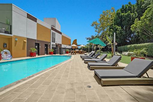 A pool with sun loungers in front of a building.