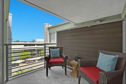 A balcony with two chairs and a small table.