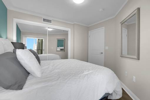 A bedroom with a large bed and a mirror on the wall.