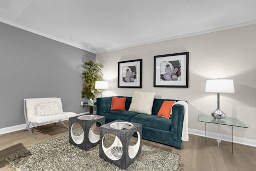 A living room with a green couch, a white chair, and a glass table.