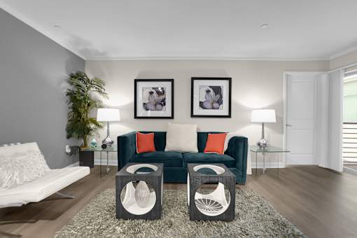A living room with a green couch and two framed pictures on the wall.