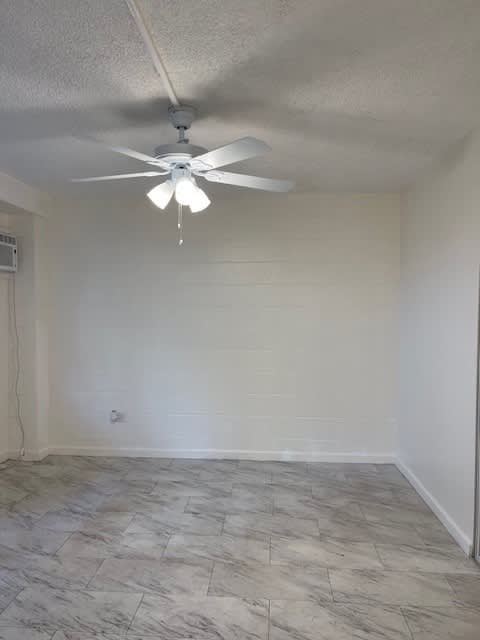 A room with a ceiling fan and tile flooring.