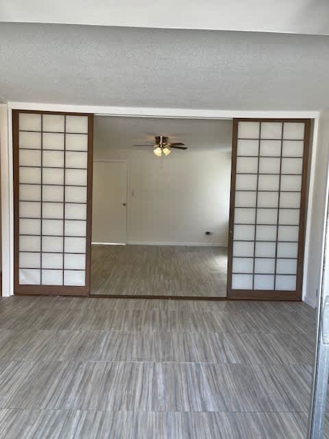 A room with a ceiling fan and sliding doors.