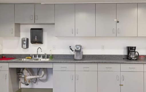 A kitchen with white cabinets and a grey countertop.