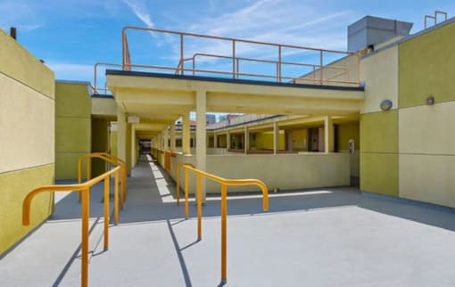 A yellow building with a metal railing and orange handrails.